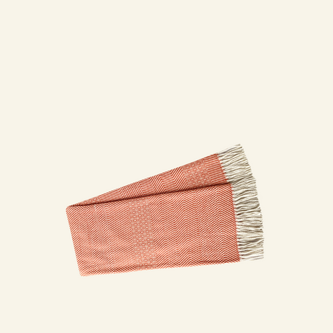 A red woven throw blanket with a checkered pattern and fringe detailing.