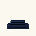 Navy blue 4-piece cooling sheets made with cooling technology and moisture-wicking fabrics folded on a cream background.