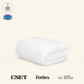 Folded white comforter on a beige background with a 2025 Bedding Awards Winner badge and a Space Foundation Certified Space Technology badge. In addition, a CNET logo, Forbes logo, and Sleep Doctor logo highlight publications that the UltraCool Comforter has been featured in.