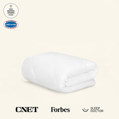 Folded white comforter on a beige background with a 2025 Bedding Awards Winner badge and a Space Foundation Certified Space Technology badge. In addition, a CNET logo, Forbes logo, and Sleep Doctor logo highlight publications that the UltraCool Comforter has been featured in.