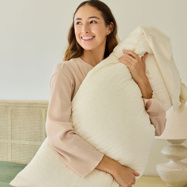 A happy woman hugging a Avec pillow with a linen viscose pillowcase on it.
