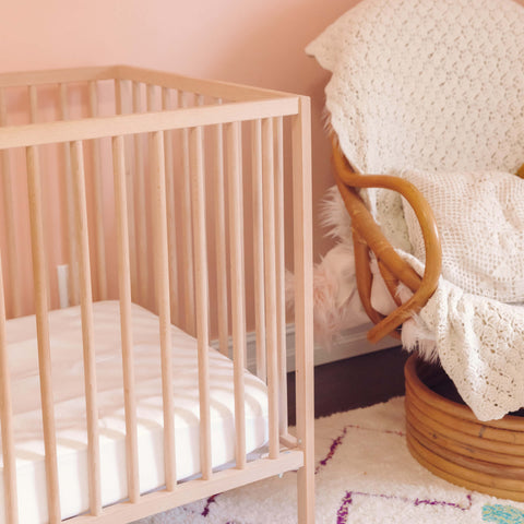 A baby's room with a rocking chair and crib fitted with a Slumber Cloud Core Mattress Protector - Crib